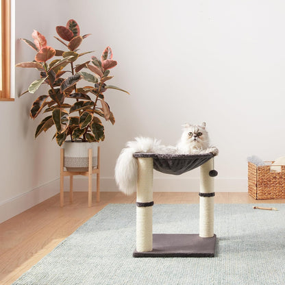 Grey cat relaxing in elevated hammock of grey cat tower with scratching posts in living room