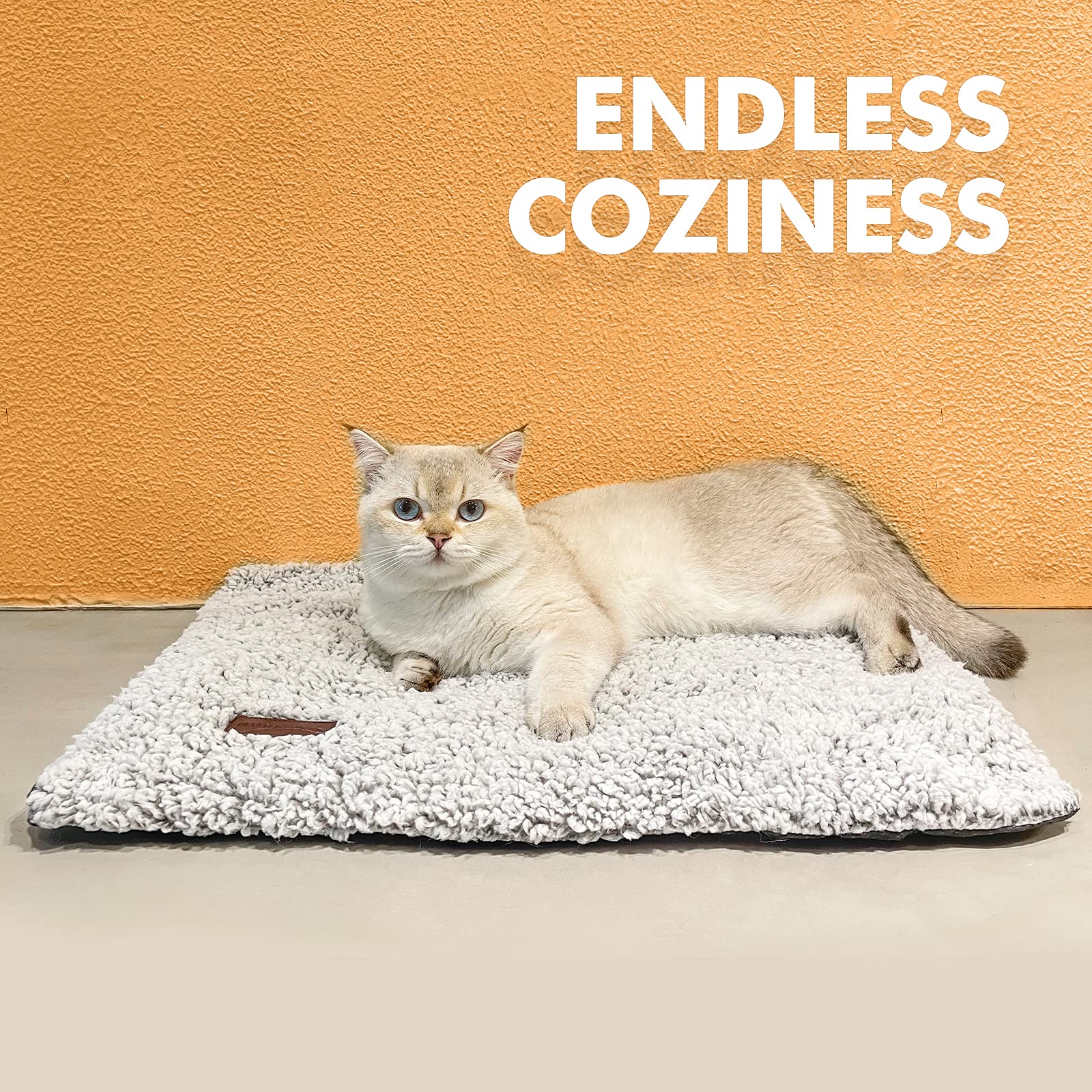 Black and white cat lying on a self-warming grey pet bed with ultra-soft fleece surface